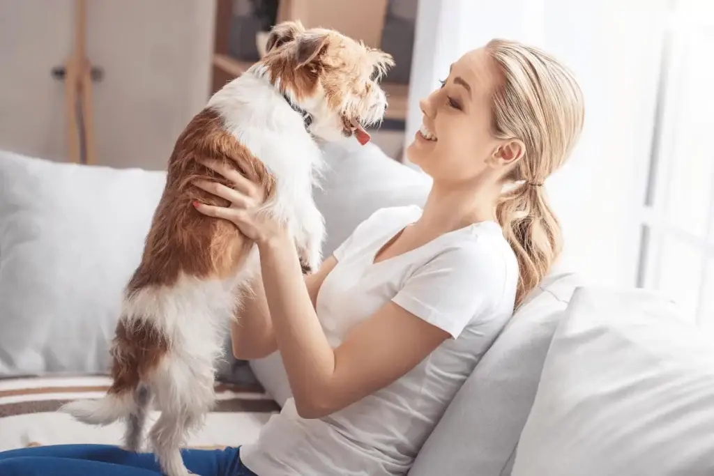 Female college student at home with her pet dog on the couch