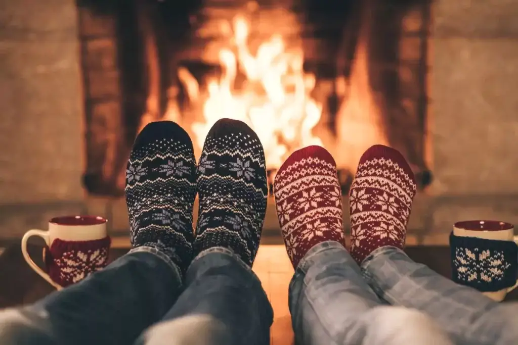 couple wearing colorful socks in front of fire place