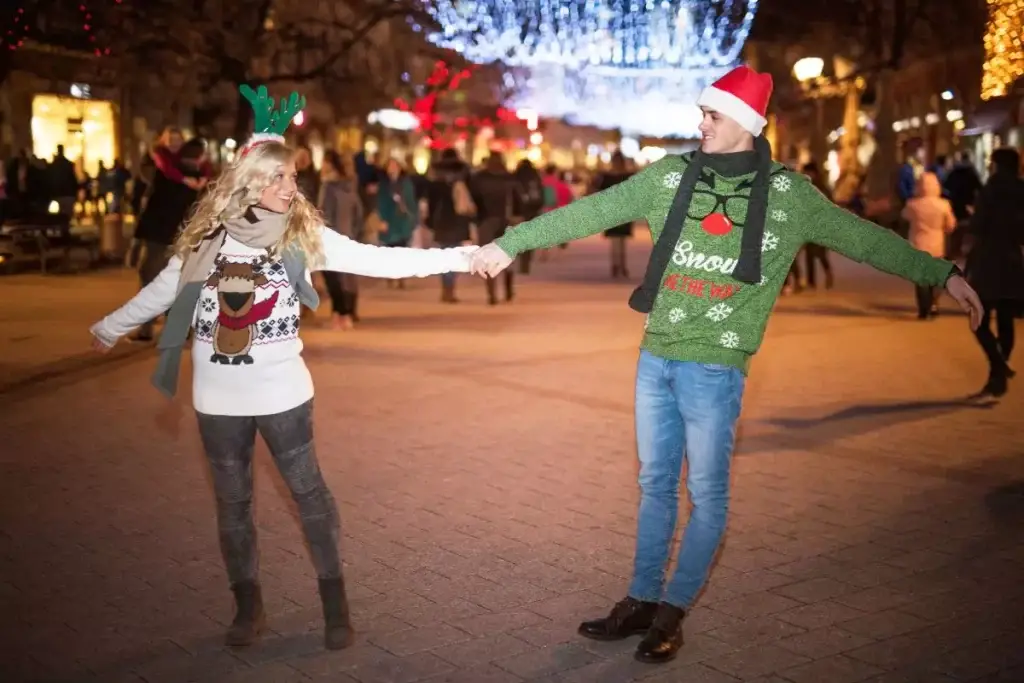 couple having fun outdoors wearing christmas sweaters