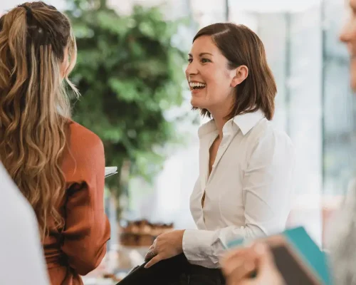 A female executive in business attire laughing, now that she's in therapy for executive women at Compass Psychological Services.